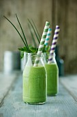 Vegan detox herb soup in glass bottles with straws (low-carb)