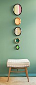 Biedermeier-Stoffmuster in ovalen Bilderrahmen über Polsterhocker an pastellgrüner Wand