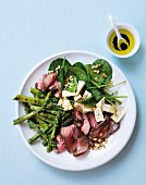 A salad with green asparagus, leaf spinach, beef fillet and feta cheese
