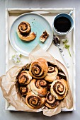 Sweet yeast swirls with a brown sugar, cinnamon and pecan nut filling on a tray with coffee