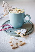 A mug of white hot chocolate with Christmas tree biscuits