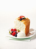 A slice of angel food cake with berries and cream
