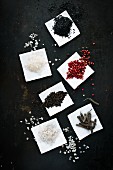 Assorted types of salt and pepper on paper
