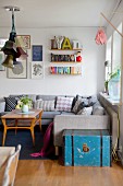 Gemütliche Wohnzimmerecke mit grauer Couch, String-Regal und Retroflair