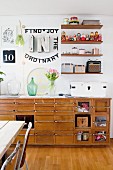 Retro sideboard against wall decorated with String shelves, collection of Russian dolls and vintage illuminated letters