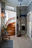 Patterned wallpaper, wooden floor and home-made Advent calendar on handrail of stair in traditional hallway