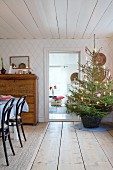 Decorated Christmas tree in basket in low-ceilinged interior
