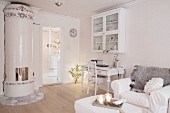 Desk below wall-mounted cabinet and armchair next to Swedish tiled stove