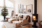 Fire in log-burning stove, pale sofa set and decorated Christmas tree in living room