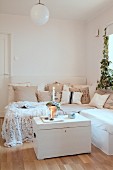 Ecksofa mit Dekokissen und weiße Truhe mit Kerzendeko in skandinavischem Wohnzimmer