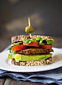 A vegan burger sandwich on wholemeal sourdough bread with avocado and tomato