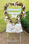 Heart-shaped wreath decorated with flowering bulbs on garden chair