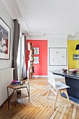 Dining area in restored period apartment with stucco ceiling, herringbone parquet floor and colourful accent walls