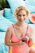 A blonde woman in a salmon-coloured top drinking a smoothie