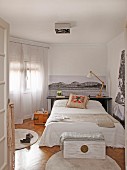 Schlafzimmer mit schwarz-weißen Fotoaufnahmen, Bett mit Dekokissen und Holztruhe auf rundem Teppich