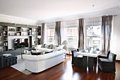 White sofa set, shelving, dining table and grey loose-covered chairs in elegant lounge area