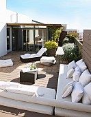 Elegant lounger and benches with white cushions on sunny roof terrace