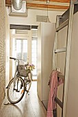 Bicycle and ladder leading to bed in bright entrance to loft apartment