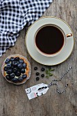 A cup of coffee and a blueberry tartlet