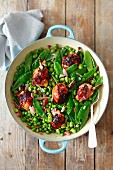 Chicken thights with shallots, broad beans, peas, mangetout and raisins