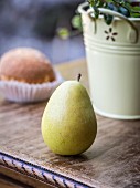 A pear and a Spanish Magdalena cupcake on a wooden table