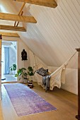 Hammock, houseplant and ethnic mask in high-ceilinged attic room