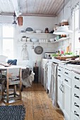 Bright country-house kitchen with curtains on base units and dining table