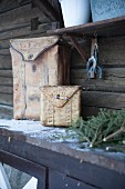 Zwei Taschen aus Birkenrinde auf einem Tisch vor dem Holzhaus