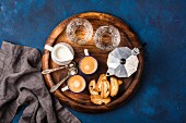 Coffee espresso in cups with italian cantucci, cookies and milk in jug on wooden serving round board