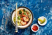 Asian Ramen noodles with Prawns and greens on blue background