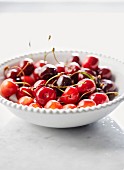 Plate of fresh cherries on marble countertop