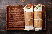 Tortilla wraps sandwiches with fresh vegetables on wooden cutting board