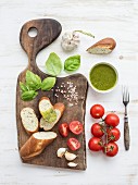 Homemade pesto sauce, fresh bread, cherry tomatoes on wooden cutting board