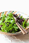 Mixed leaf salad in a salad bowl with cutlery