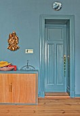Low sideboard against blue-grey wall and next to door of same colour