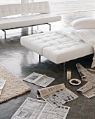 White folding sofas and newspapers scattered on concrete floor