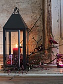 Lantern festively decorated with candle, twigs and pink accessories