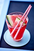 A watermelon drink in a glass with straws