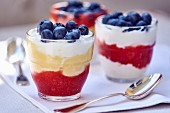 A layered dessert made of strawberry sauce, vanilla cream and blueberries