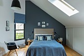 Double bed with blue cover in attic room