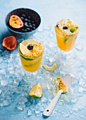 An orange drink with passionfruit, lime and blueberries