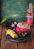 A spicy beetroot burger served with corn on the cob