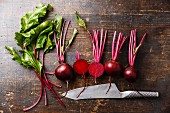 Red Beetroot with herbage green leaves and Kitchen knife on wooden background