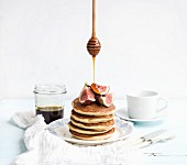 Turm aus Pancakes mit frischen Feigen und fliessendem Honig