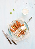 Roasted carrots with cream cheese sauce on blue plate over light blue painted wooden background