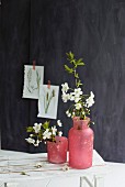 Blütenzweig in roten Vasen vor schwarzer Wand