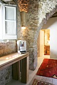 Rustikaler Durchgang in restauriertem Steinhaus mit Einblick in beleuchtetes Badezimmer