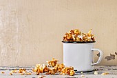 Prepared caramelized sweet popcorn served in vintage white enameled mug