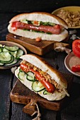 Two of homemade hot dogs with sausage, fried onion, tomatoes and cucumber, served with ingredients