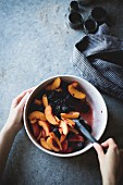 Mixing peaches and blackberries in a mixing bowl